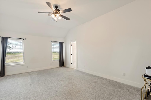 unfurnished room featuring vaulted ceiling, plenty of natural light, light carpet, and baseboards