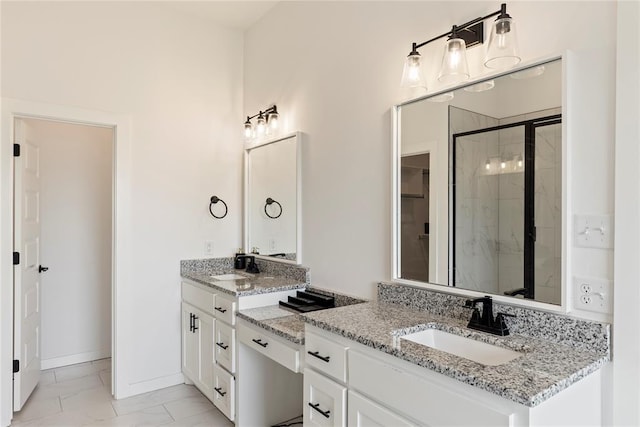 full bath featuring a shower stall, marble finish floors, two vanities, and baseboards