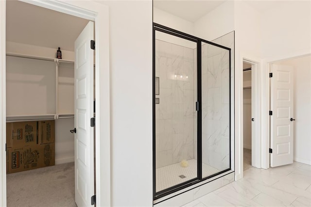bathroom with a marble finish shower, a spacious closet, and marble finish flooring