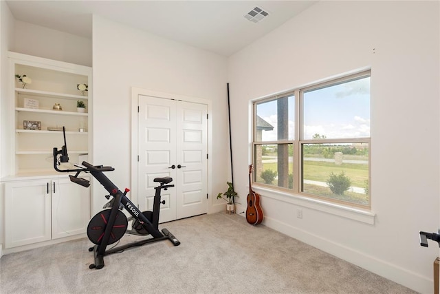 exercise room featuring light carpet and baseboards