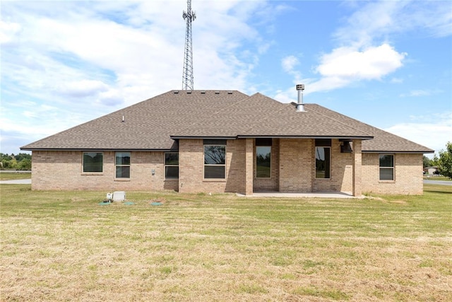 rear view of house with roof with shingles, a patio, brick siding, and a lawn