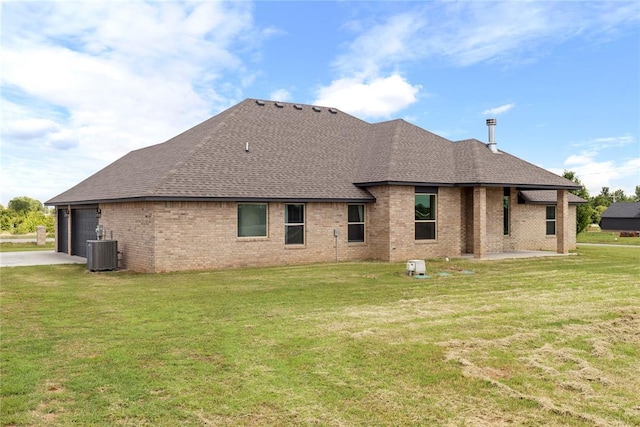 back of property with brick siding, roof with shingles, an attached garage, and a yard