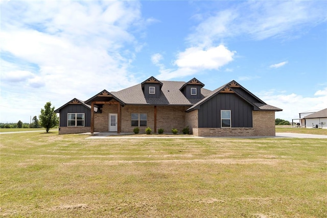 view of front of home with board and batten siding, a front yard, brick siding, and roof with shingles