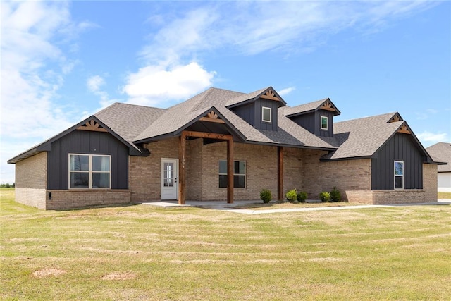 view of front of property with board and batten siding, a front yard, and brick siding