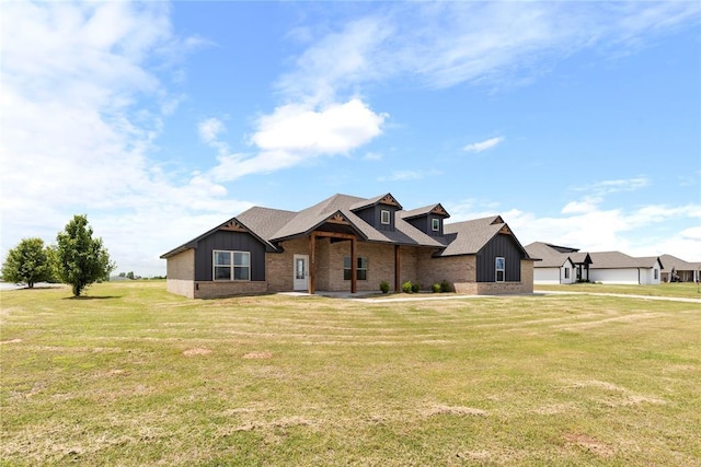 view of front facade featuring board and batten siding, a front yard, brick siding, and a shingled roof