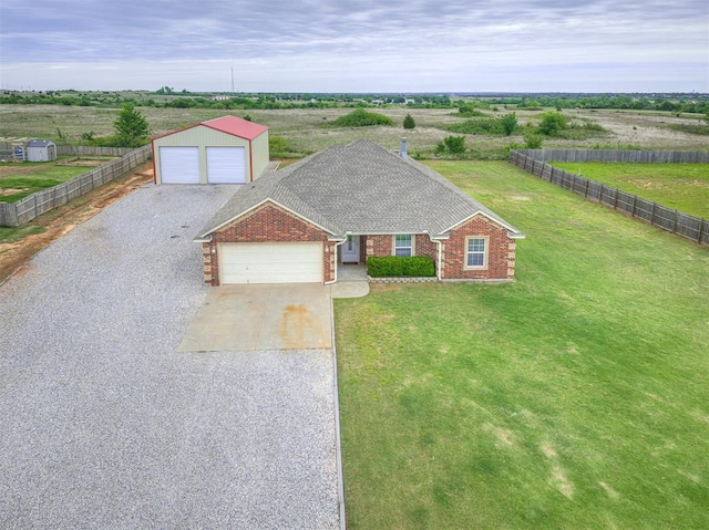 view of front of property with an outdoor structure, brick siding, driveway, a view of countryside, and roof with shingles