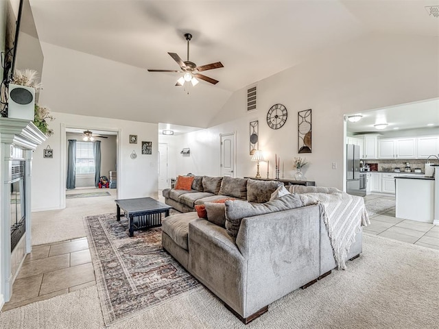 living area with ceiling fan, light tile patterned floors, light colored carpet, and high vaulted ceiling
