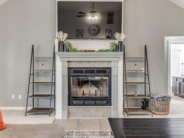 detailed view of a tile fireplace, ceiling fan, and baseboards