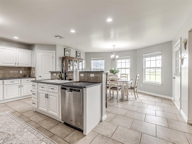 kitchen featuring dishwasher, a sink, a chandelier, tasteful backsplash, and dark countertops