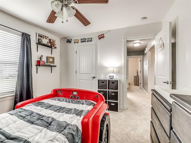bedroom featuring light carpet, multiple windows, and a ceiling fan