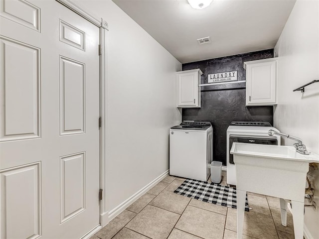 laundry room with washing machine and clothes dryer, cabinet space, light tile patterned floors, and baseboards