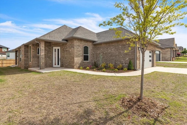 french provincial home featuring brick siding, concrete driveway, a garage, and roof with shingles