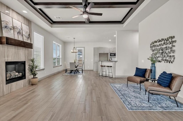 sitting room with coffered ceiling, light wood finished floors, ceiling fan, recessed lighting, and a fireplace