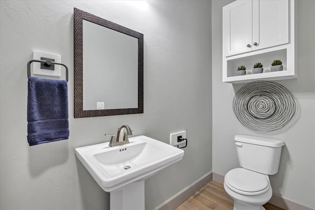 bathroom with wood finished floors, toilet, a sink, and baseboards