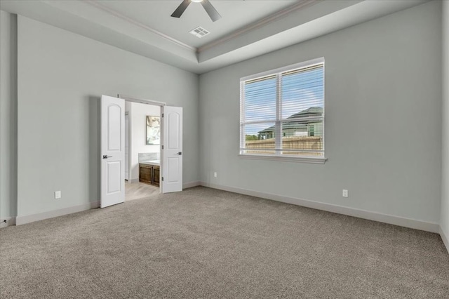 unfurnished bedroom with light carpet, ornamental molding, a raised ceiling, and baseboards