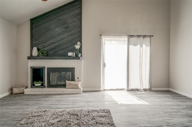 7301 Kings Manor Ct, Oklahoma City, OK 73132 - unfurnished living room featuring wood finished floors, baseboards, a fireplace, and a textured ceiling