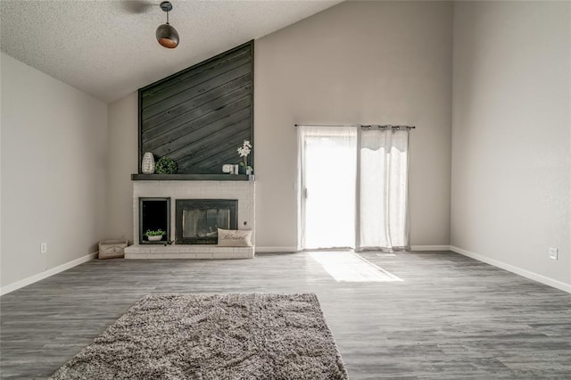 7301 Kings Manor Ct, Oklahoma City, OK 73132 - unfurnished living room featuring wood finished floors, a brick fireplace, baseboards, a textured ceiling, and high vaulted ceiling