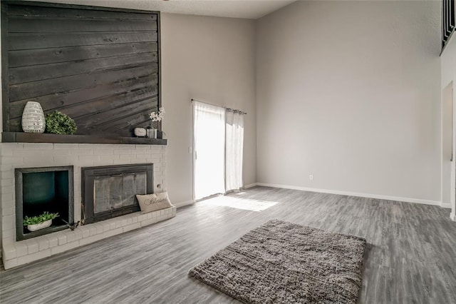 7301 Kings Manor Ct, Oklahoma City, OK 73132 - unfurnished living room with wood finished floors, a brick fireplace, baseboards, and a towering ceiling