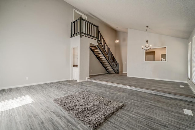 7301 Kings Manor Ct, Oklahoma City, OK 73132 - unfurnished living room with stairway, lofted ceiling, a chandelier, wood finished floors, and baseboards
