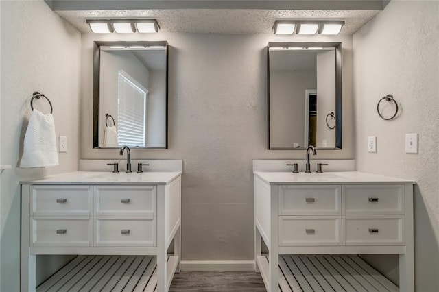7301 Kings Manor Ct, Oklahoma City, OK 73132 - bathroom featuring two vanities, wood finished floors, a textured wall, and baseboards