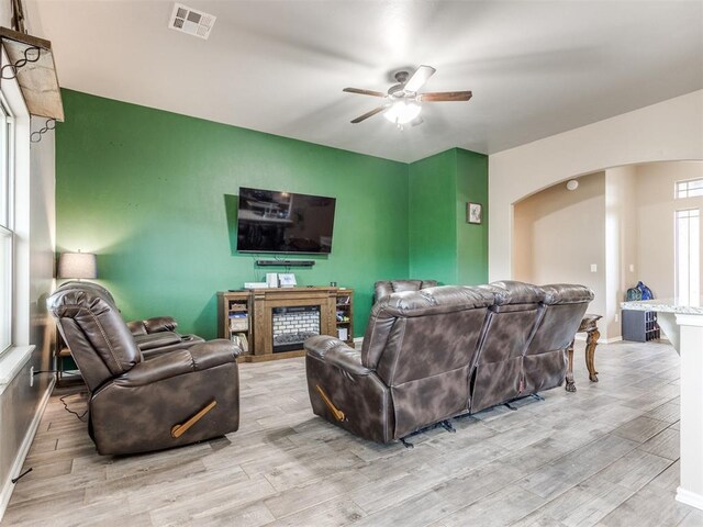 5702 Cedar Tree Cir, Guthrie, OK 73044 - living room with arched walkways, ceiling fan, light wood-type flooring, a fireplace, and baseboards