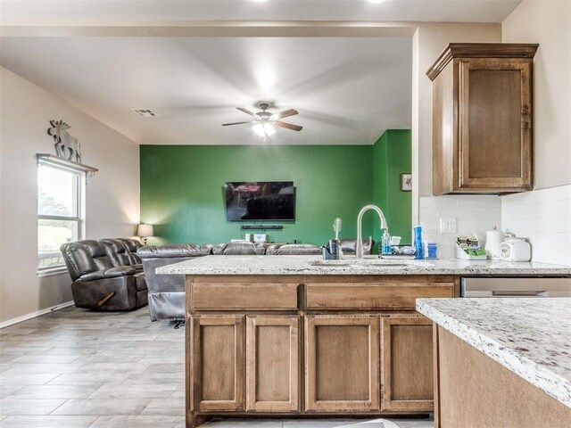 5702 Cedar Tree Cir, Guthrie, OK 73044 - kitchen featuring a sink, open floor plan, a ceiling fan, decorative backsplash, and light stone countertops