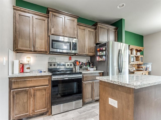 5702 Cedar Tree Cir, Guthrie, OK 73044 - kitchen with appliances with stainless steel finishes, decorative backsplash, light stone counters, a kitchen island, and recessed lighting
