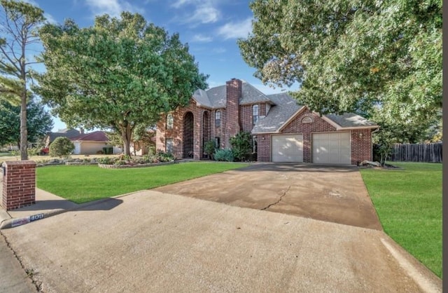 traditional-style home featuring driveway, brick siding, an attached garage, and a chimney