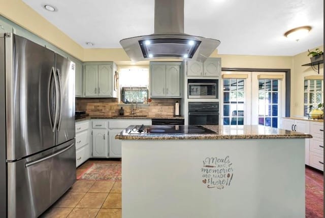 kitchen with black appliances, island range hood, a sink, and plenty of natural light