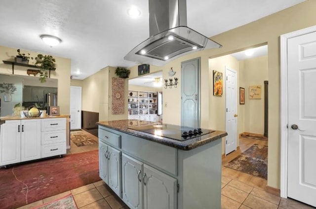 kitchen featuring island range hood, tile patterned floors, dark countertops, and black electric cooktop