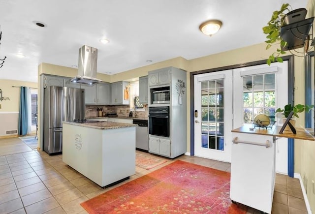 kitchen with black appliances, island range hood, gray cabinetry, light tile patterned floors, and a kitchen island