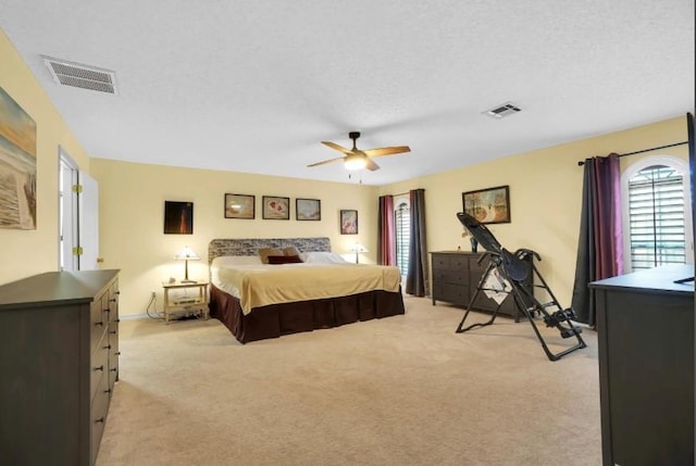 bedroom featuring light carpet, a ceiling fan, a textured ceiling, and baseboards