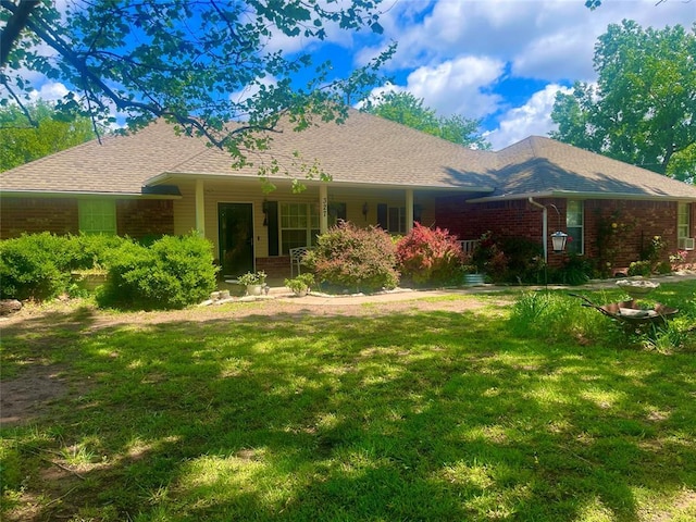 view of front facade with brick siding, a front yard, and a porch
