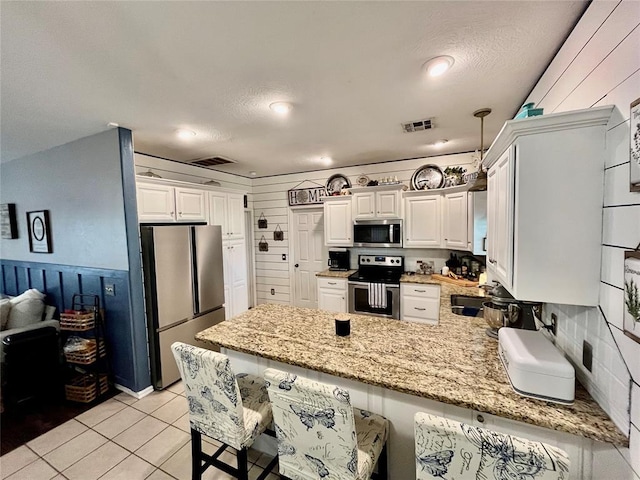327 Englebretson Ln, Tuttle, OK 73089 - kitchen featuring stainless steel appliances, a peninsula, light stone countertops, and white cabinetry