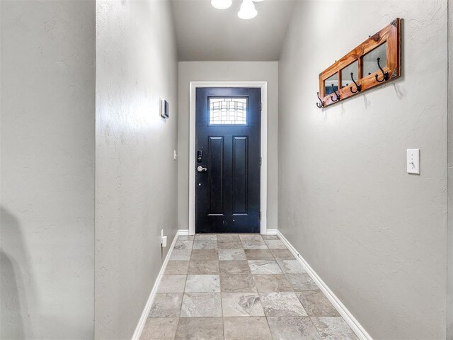 doorway with stone finish floors and baseboards