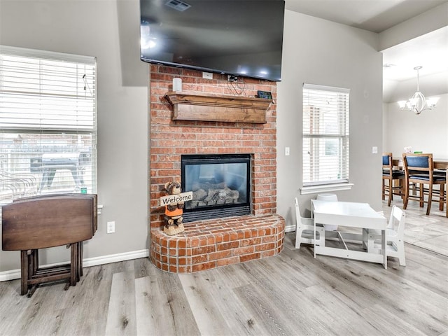 living area with wood finished floors, a chandelier, a fireplace, and baseboards
