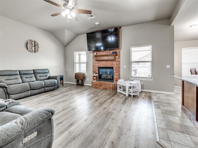 living area with a ceiling fan, light wood-style flooring, a fireplace, baseboards, and lofted ceiling