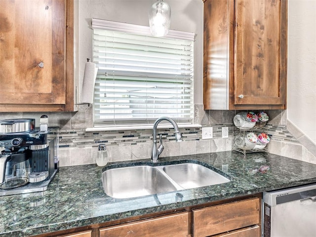 kitchen featuring stainless steel dishwasher, a sink, brown cabinetry, decorative backsplash, and healthy amount of natural light