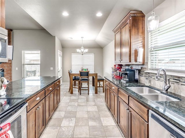 kitchen featuring a sink, stainless steel appliances, a chandelier, pendant lighting, and lofted ceiling