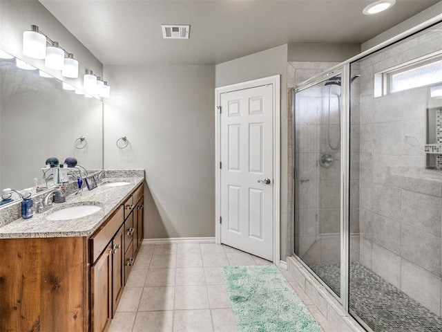 full bathroom with tile patterned floors, a stall shower, baseboards, and double vanity