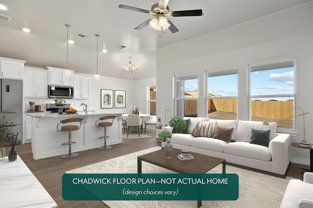 living room with ceiling fan, recessed lighting, light wood-style floors, high vaulted ceiling, and a chandelier