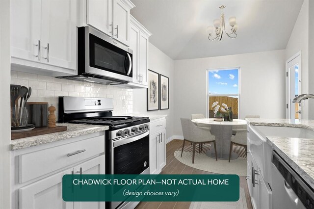 kitchen with appliances with stainless steel finishes, backsplash, a sink, a chandelier, and baseboards