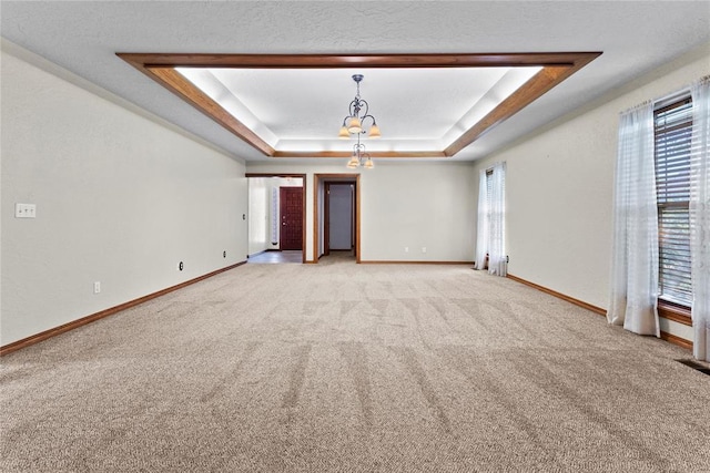 2001 Saber Ln, Weatherford, OK 73096 - spare room featuring a raised ceiling, light carpet, a chandelier, and baseboards