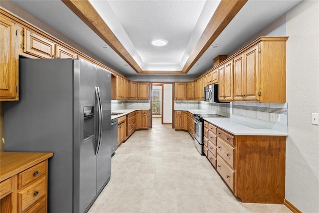 2001 Saber Ln, Weatherford, OK 73096 - kitchen with appliances with stainless steel finishes, light countertops, brown cabinetry, a raised ceiling, and backsplash