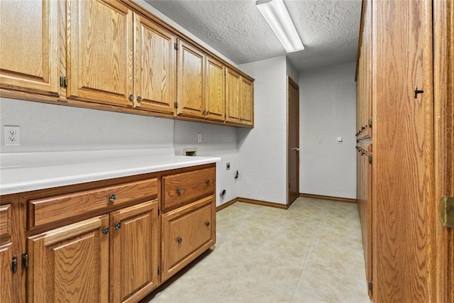 2001 Saber Ln, Weatherford, OK 73096 - laundry room featuring hookup for an electric dryer, cabinet space, a textured ceiling, baseboards, and hookup for a washing machine