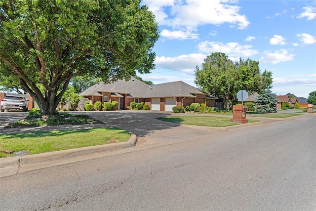 2001 Saber Ln, Weatherford, OK 73096 - ranch-style home featuring a garage, asphalt driveway, a front lawn, and brick siding