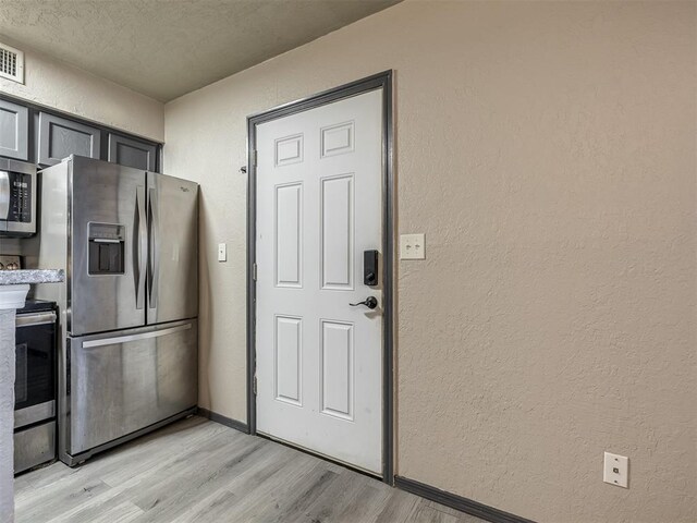 11530 N May Ave Unit D303, Oklahoma City, OK 73120 - kitchen with appliances with stainless steel finishes, a textured wall, light wood-style flooring, and a textured ceiling