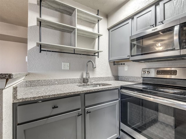 11530 N May Ave Unit D303, Oklahoma City, OK 73120 - kitchen with appliances with stainless steel finishes, gray cabinets, open shelves, and a textured wall