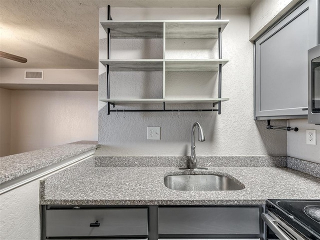 11530 N May Ave Unit D303, Oklahoma City, OK 73120 - kitchen with gray cabinets, open shelves, a textured wall, range with electric cooktop, and light stone countertops