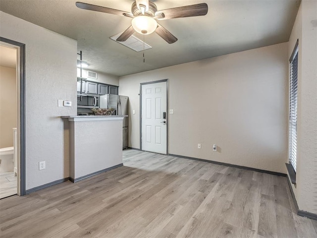 11530 N May Ave Unit D303, Oklahoma City, OK 73120 - kitchen with a ceiling fan, appliances with stainless steel finishes, light wood-style flooring, light countertops, and a textured wall